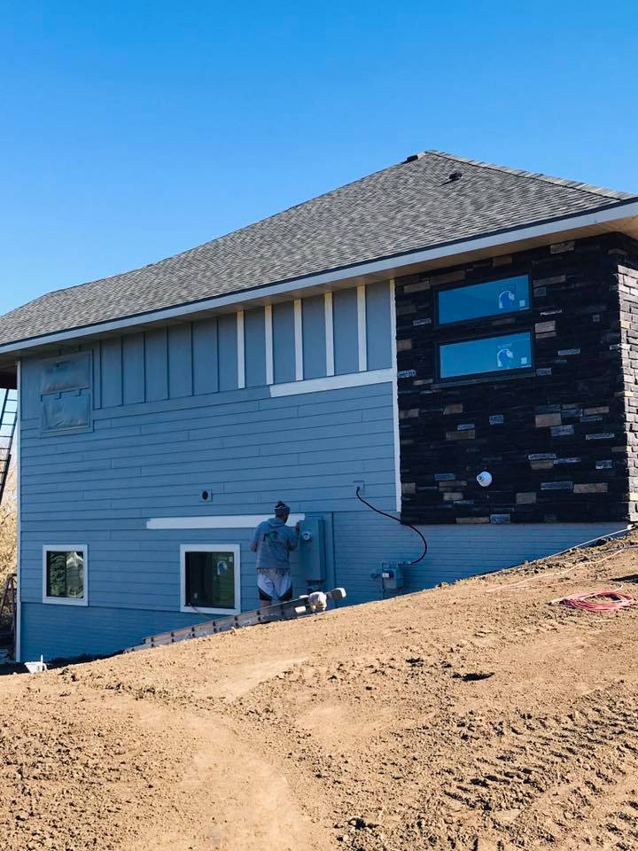 RPS Painting crew member cutting in trim on a blue siding exterior in progress, Sioux Falls SD.